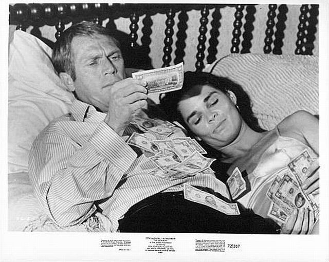 Steve McQueen (as Doc McCoy) and 
Ali MacGraw (as Carol McCoy)
in bed covered in money.